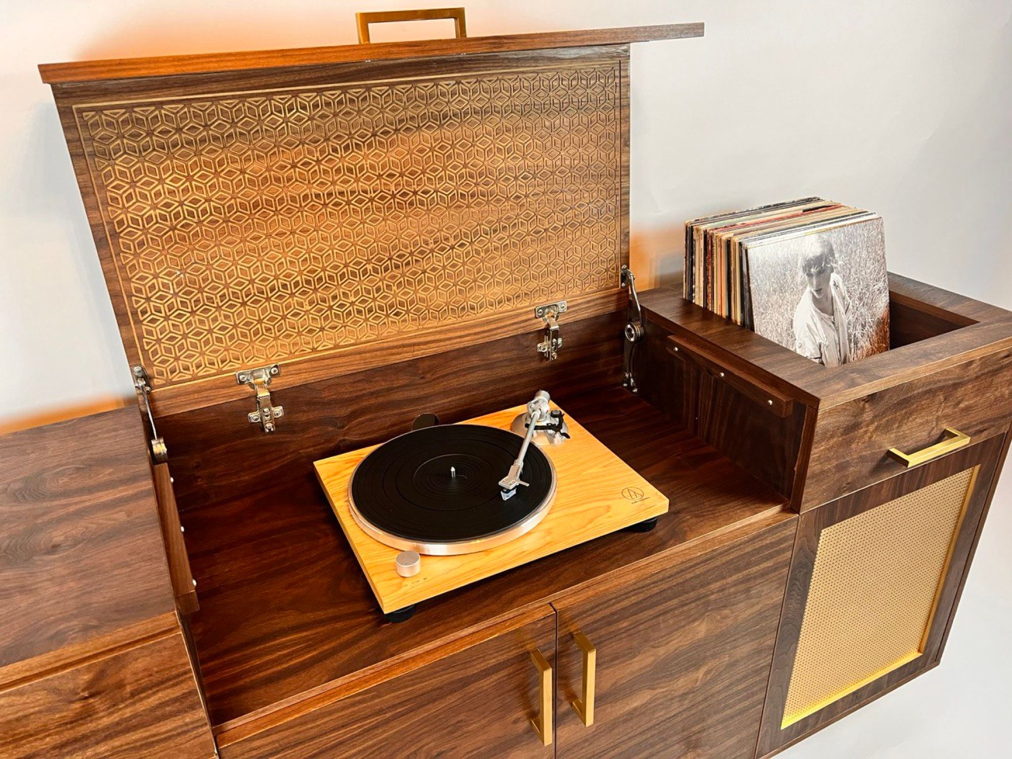 Lift-up lid of a walnut console revealing a turntable and record storage