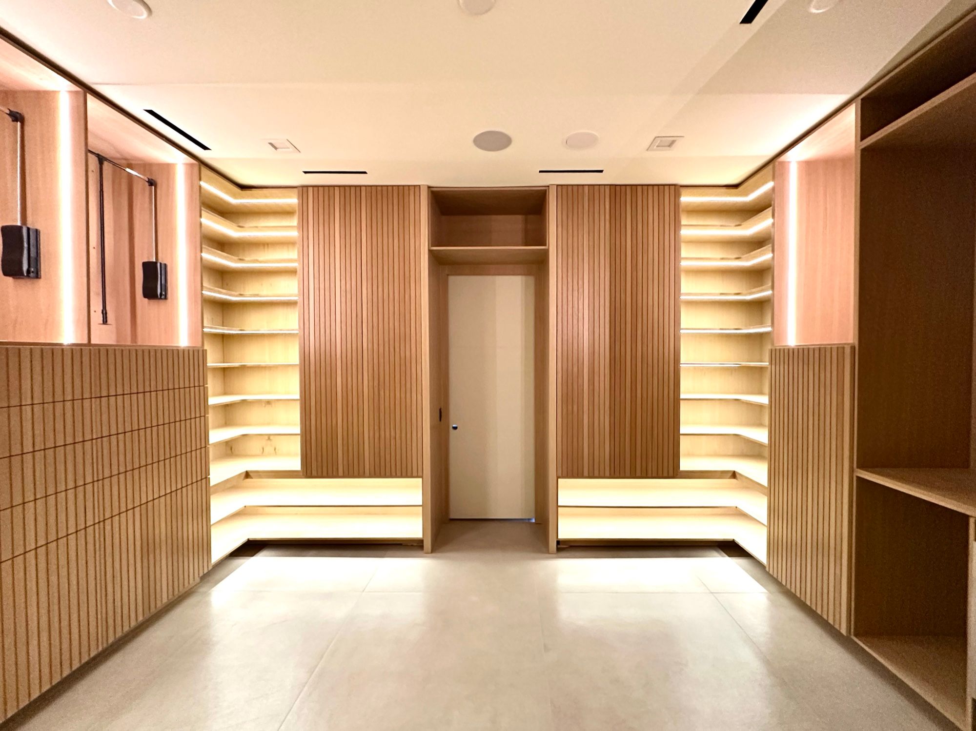 White oak dressing room with lit shoe shelving and fluted panels